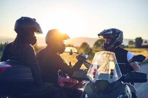 Motorcyclists greeting each other on the road at sunset