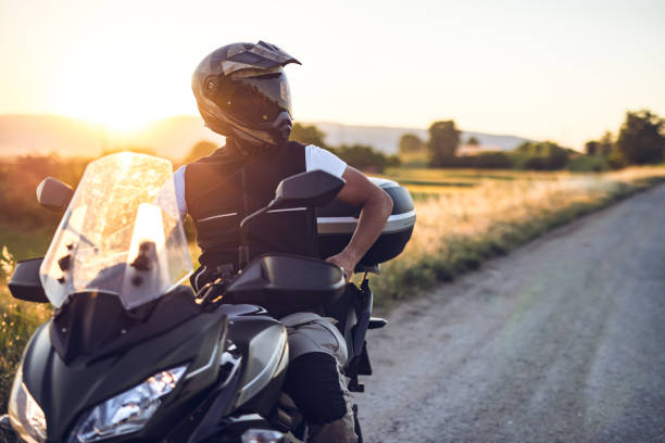 mann auf dem motorrad genießt in fahrt bei sonnenuntergang - motorradfahrer stock-fotos und bilder