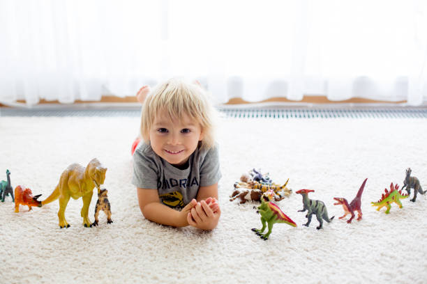 istock Blond toddler child, playing with dinosaurs at home 1322660747