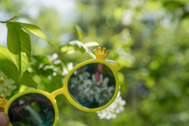 istock A large white bird cherry flower is visible through yellow sunglasses 1322661837