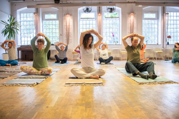 grupo de personas estirando las manos durante la clase de yoga - mejora personal fotografías e imágenes de stock