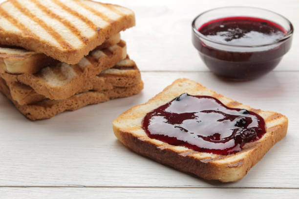 istock toasts with jam. fried crispy toasts with red jam on a white wooden table. 1322665584