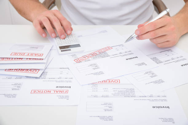 istock Close-up Of A Man Calculating Unpaid Bills Using Calculator 1322665857