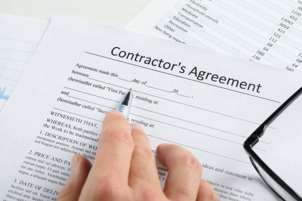 Close-up Of Hand With Pen And Eyeglasses Over Contractor Agreement Close-up Of Hand With Pen And Eyeglasses Over Contractor Agreement independence document agreement contract stock pictures, royalty-free photos & images