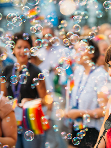 Crowd smiling and holding rainbow flags during the Belgrade Pride Festival. 
Soap bubbles, and balloons on the street party. Blurred motion
Belgrade, Serbia, on September 16th, 2018