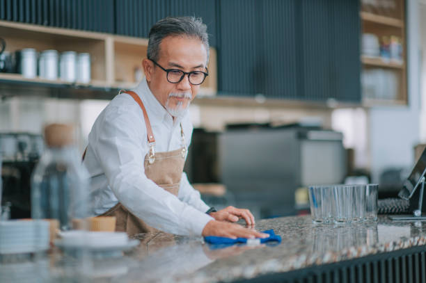 asian chinese cafeteria working senior man cleaning kitchen counter with towel