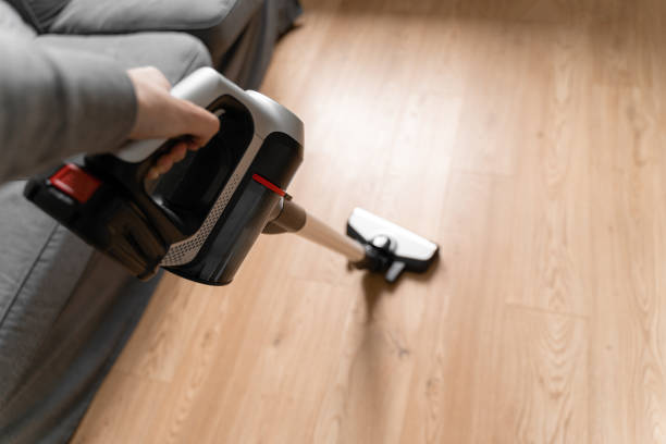 Cleaning wooden floor with wireless vacuum cleaner. Handheld cordless cleaner. Household appliance. Housework modern equipment stock photo