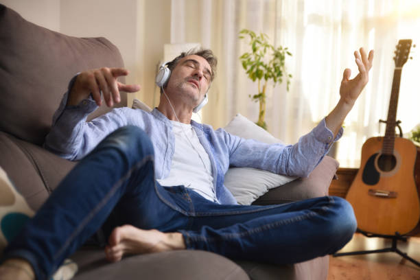 homem deitado no sofá absorto ouvindo música tranquila - relaxation working humor sofa - fotografias e filmes do acervo