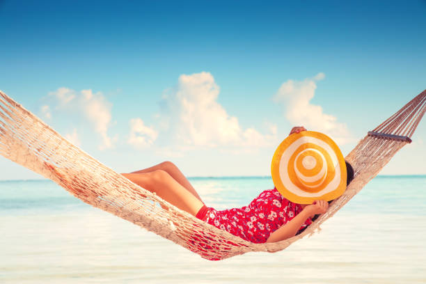 istock Young girl resting in a hammock under tall palm trees, tropical beach 1322673115