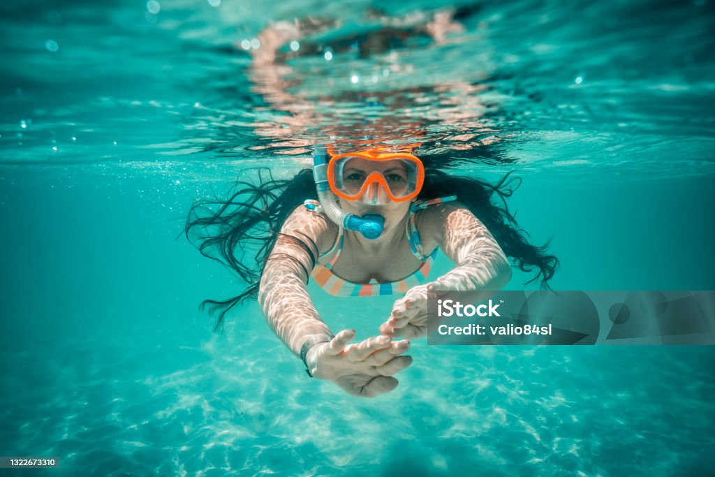 Underwater view of beautiful woman swimming in blue ocean water Snorkeling Stock Photo