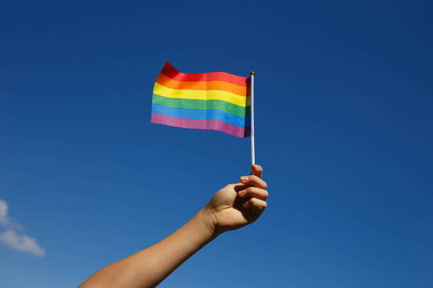 istock small lgbt flag in the hand against the blue sky 1322673703