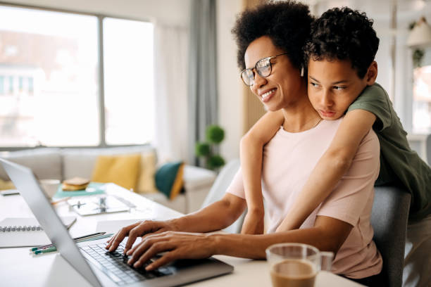 istock Son hugging his working mother while she is working from home 1322676611