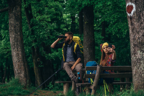 istock Hikers sitting on a bench in the forest and making a break while using a smartphone 1322677870