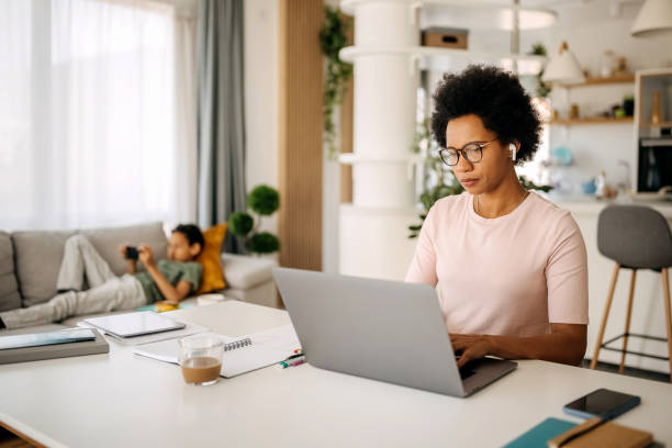 istock Mother working from home while son is laying on the sofa using mobile phone 1322678739