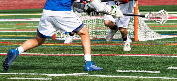 A high schhol boy lacrosse player taking a shot on goal during a game.