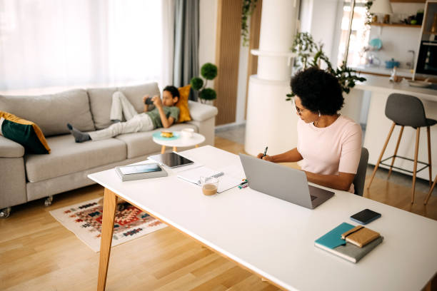 istock Mother working from home while son is laying on the sofa using mobile phone 1322679593