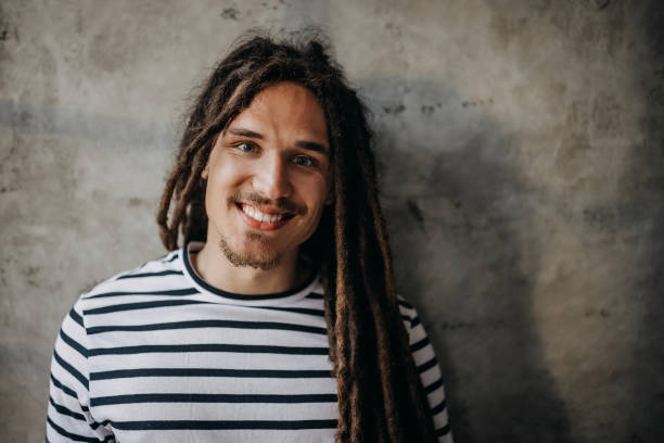 istock Smiling man with dreadlocks posing for a shot in front of concrete wall 1322683236