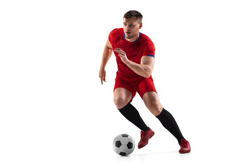Powerful, flying and running above the field. Young football soccer player in action, motion isolated on white background. Concept of sport, movement, energy and dynamic, healthy lifestyle.