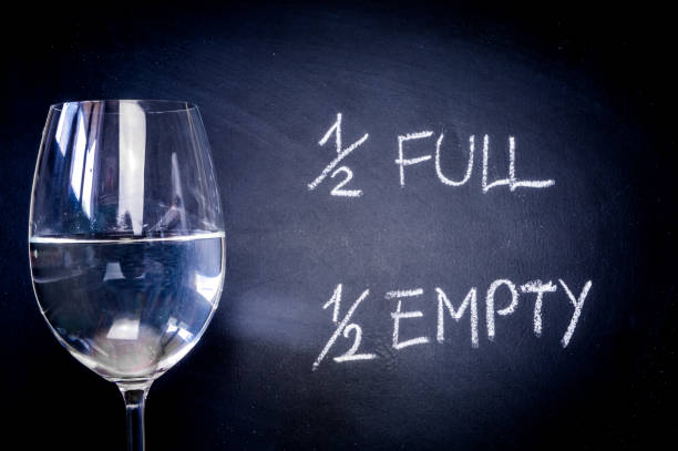 istock Half-full or half-empty glass of water, with text written on a blackboard, showing optimism or pessimism, concept 1322685529