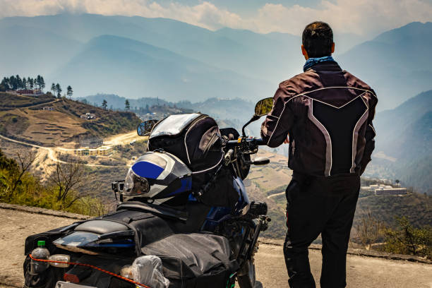 istock man motorcyclist watching valley from hill top with his loaded motorcycle and pristine natural view 1322687186