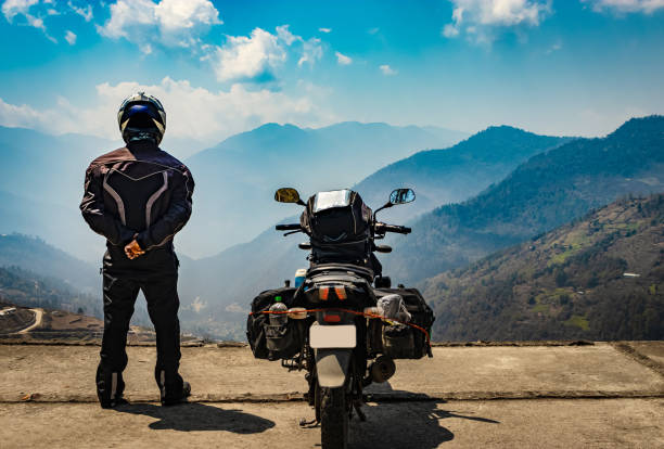 istock man motorcyclist watching valley from hill top with his loaded motorcycle and pristine natural view 1322687276