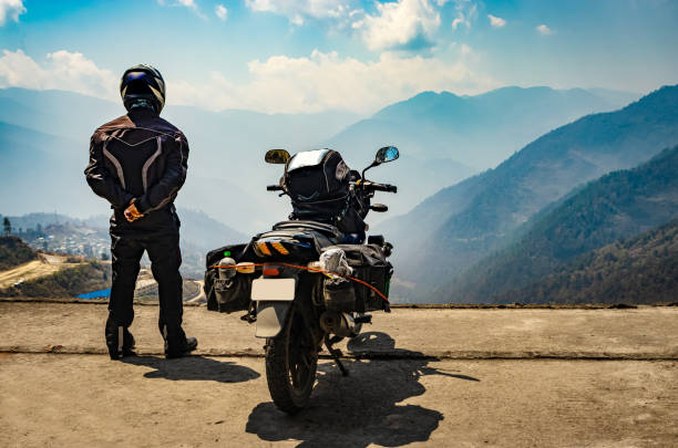 istock man motorcyclist watching valley from hill top with his loaded motorcycle and pristine natural view 1322687591