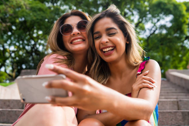 istock Two friends taking selfie with phone outdoors. 1322690367