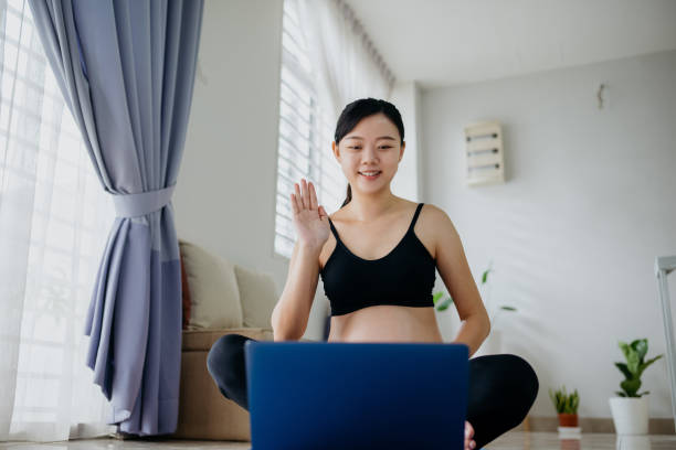 istock Pregnant woman using laptop for online exercise class at home 1322690851