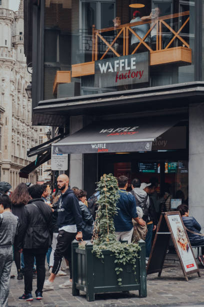 touristen schlange auf einer straße, um waffeln von waffle factory café und waffeln shop in brüssel, belgien zu kaufen. - brussels waffle belgian waffle people stock-fotos und bilder