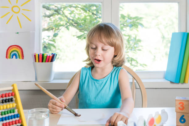 istock Funny beautiful happy child boy draws laughing with paint 1322693012