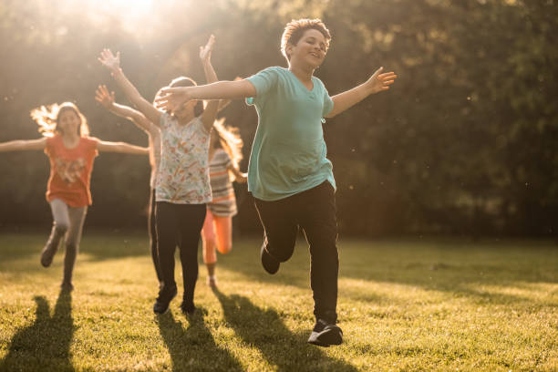 istock Children whit arms raised running in public park 1322693410