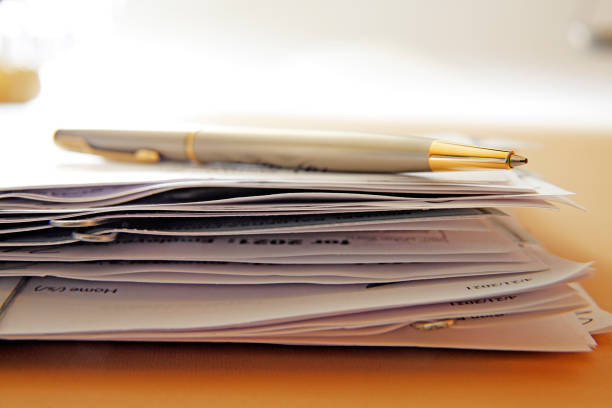 Ballpoint Pen On Top Of Stack Of Documents A ballpoint pen rests on top of a random stack of documents held together by paper clips.  Photographed with a very shallow depth of field. legal document stock pictures, royalty-free photos & images