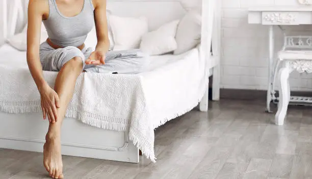 Girl in a studio. Lady with cream. Woman in a gray t-shirt. Girl sitting on a bed.