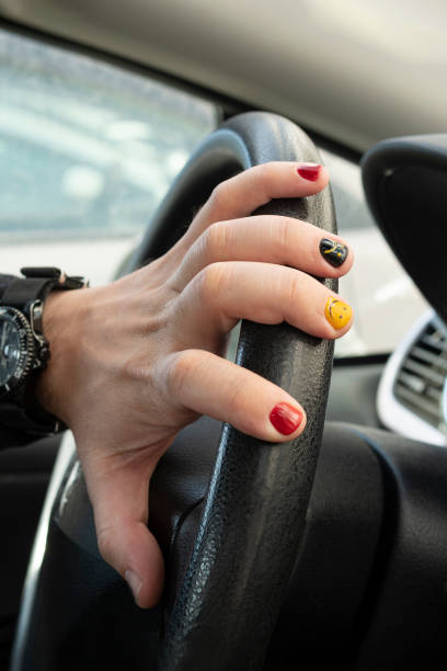 car steering wheel and hand with bright manicure. Driving car. car steering wheel and hand with bright manicure. Driving a car. rocker nails stock pictures, royalty-free photos & images