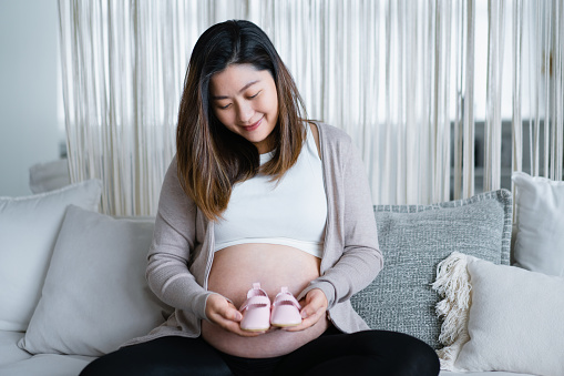 One woman, unrecognizable pregnant woman touching her belly.