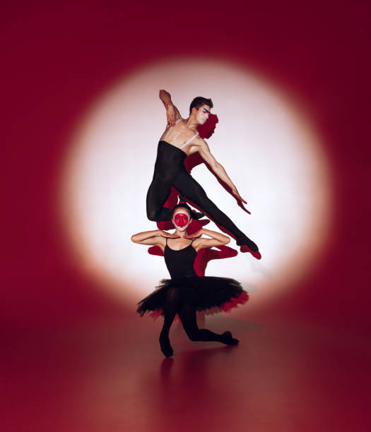 Ballet dancers dancing over red studio background. Modern design. Contemporary colorful conceptual light as rising sun at Japan. Female and male perfomers in japanese makeup. Shadow from silhouettes
