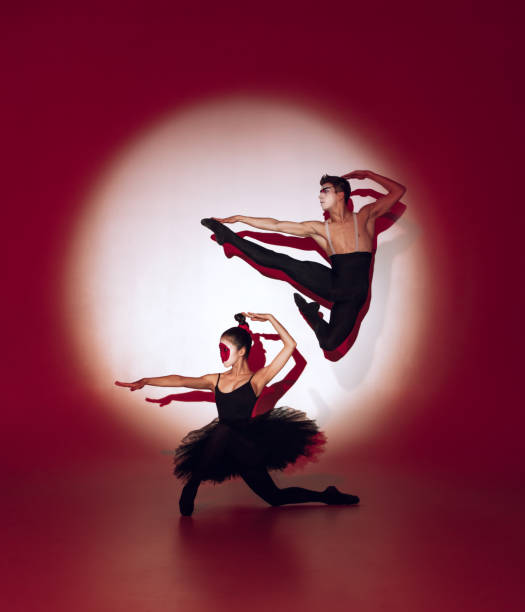 istock Ballet dancers dancing over red studio background. Modern design. Contemporary colorful conceptual light as rising sun at Japan. 1322700157