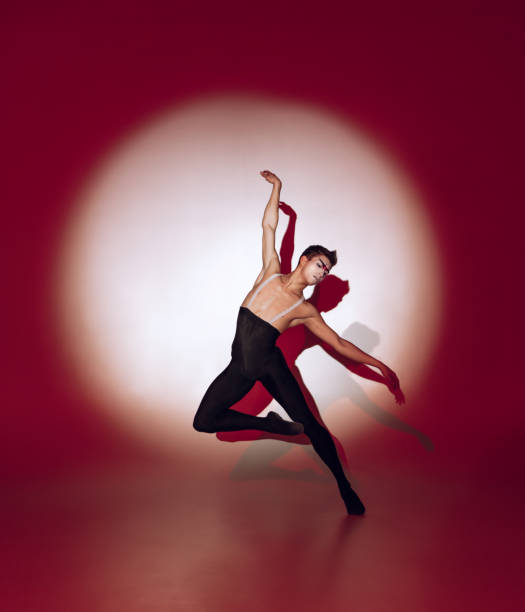istock Ballet dancer dancing over red studio background. Modern design. Contemporary colorful conceptual light as rising sun at Japan. 1322700190