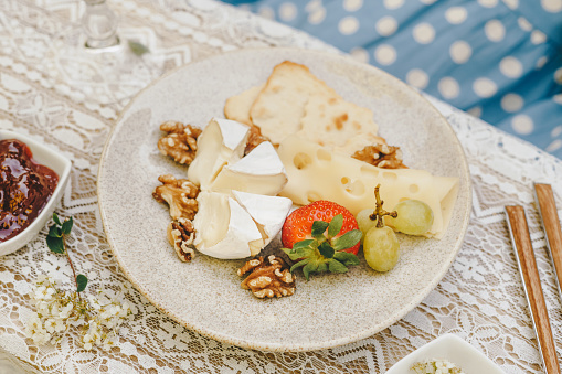 Summer picnic plate with the selection of cheeses and snacks