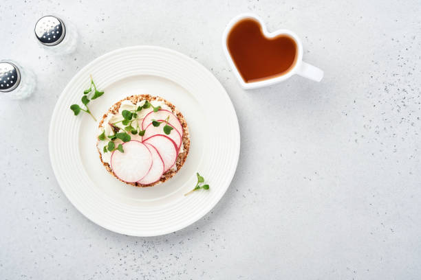 pastel de pan de trigo sarraceno crujiente sin gluten con queso crema, rábano rojo y microvegetal para un desayuno saludable sobre fondo de piedra gris. vista desde arriba. concepto vegano y alimentación saludable. - radish vegetable portion circle fotografías e imágenes de stock