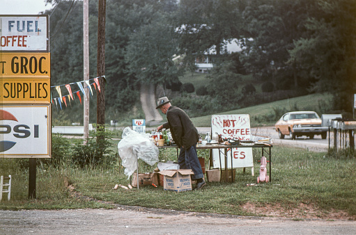 Franklin, North Carolina, USA - September 6, 1977: A Man sets up a table to sell his products by the highway in Franklin, North Carolina in late Summer. The Town of Franklin is located in the mountains of Western North Carolina and is surrounded by beautiful streams & waterfalls and offers a wealth of things to do​. It is the county seat of Macon County. The Franklin area is rich in gems and minerals and is known locally as the \