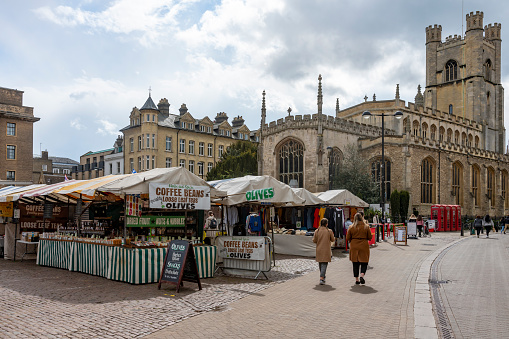 Pedestrians in the Market Square in Cambridge, England, UK, with Great St Mary's Church in the background.
