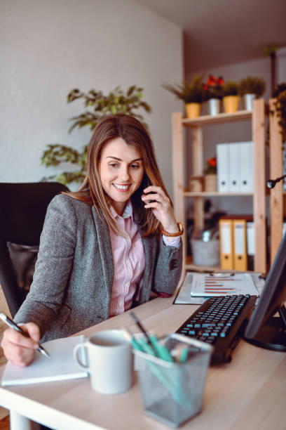 istock Businesswoman Writing Down Contact Information While Talking On Phone In Office 1322711730