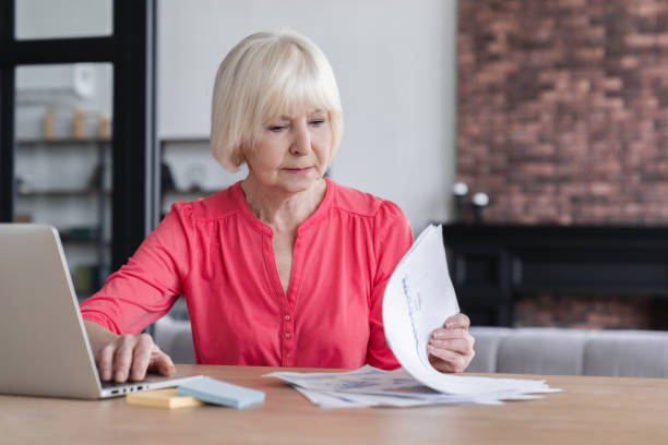 istock Confident senior old elderly businesswoman working from home, checking charts and graphs, paperwork with documents. Beautiful grandmother working in office with tables, charts, reports. 1322712036