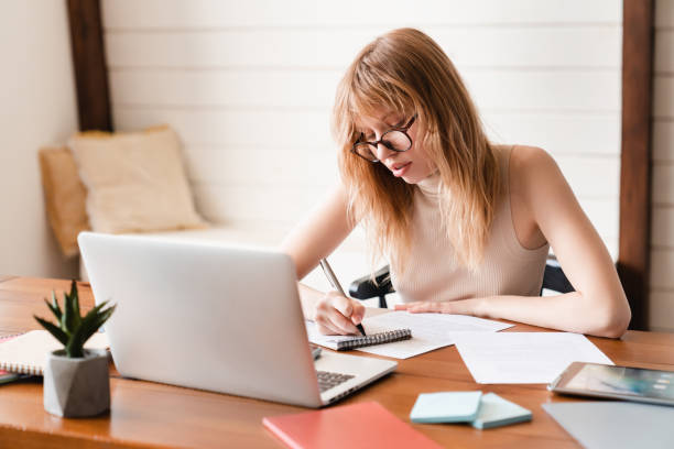 istock E-learning, webinars, college homework concept. Businesswoman tutor freelancer making notes using laptop remotely on part-time job 1322715139