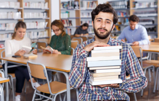 istock Portrait of bearded man with stack of books 1322715997