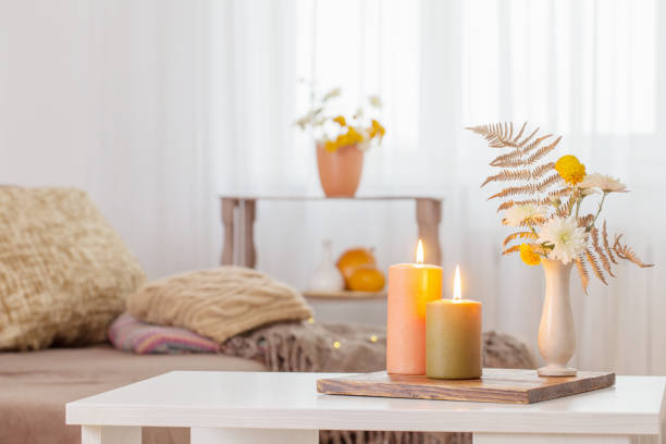 burning candles with autumn decor on white table at home