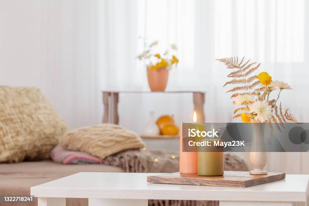 Burning Candles With Autumn Decor On White Table At Home Stock Photo - Download Image Now