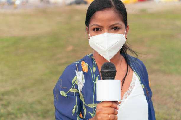 istock woman journalist in mask holding microphone 1322720429