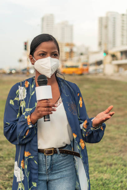 istock woman journalist in mask holding microphone 1322720472